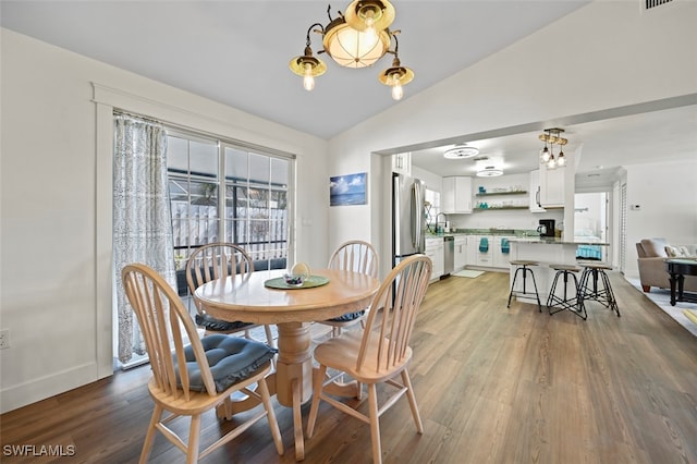 dining space with sink, vaulted ceiling, and light wood-type flooring