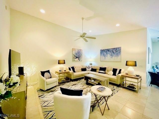 tiled living room with ceiling fan and a high ceiling