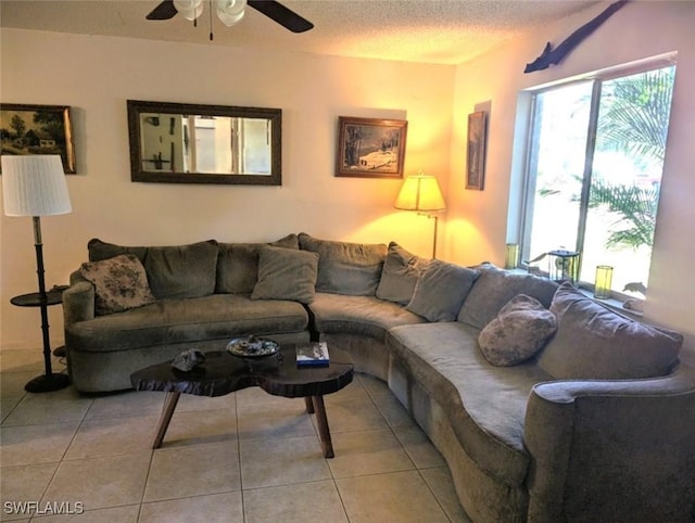 living room with light tile patterned flooring, ceiling fan, and a textured ceiling