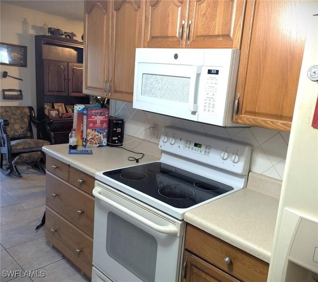 kitchen featuring tasteful backsplash, light tile patterned flooring, and white appliances