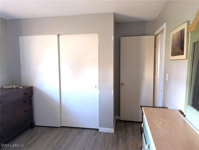 unfurnished bedroom with hardwood / wood-style flooring, a closet, and a textured ceiling