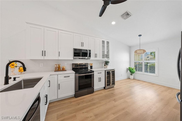 kitchen featuring wine cooler, stainless steel appliances, visible vents, white cabinets, and a sink