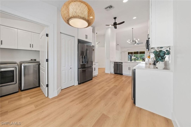 kitchen featuring visible vents, light wood-style flooring, stainless steel appliances, washing machine and dryer, and white cabinetry