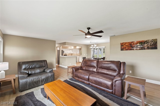 living room featuring ceiling fan with notable chandelier and light hardwood / wood-style floors