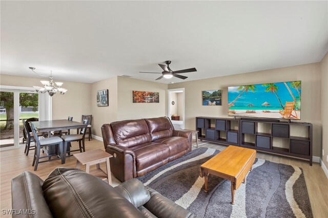 living room with ceiling fan with notable chandelier and light hardwood / wood-style floors