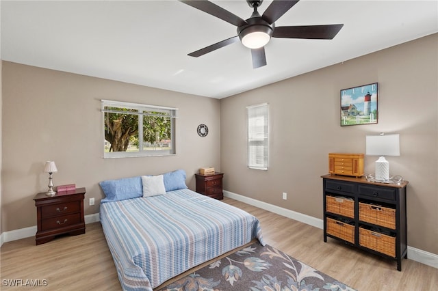 bedroom with multiple windows, ceiling fan, and light hardwood / wood-style floors