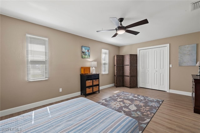 bedroom featuring a closet, wood-type flooring, and multiple windows