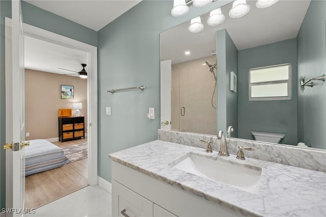 bathroom featuring an enclosed shower, vanity, toilet, and ceiling fan