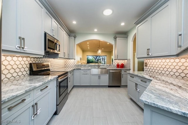 kitchen featuring stainless steel appliances, gray cabinetry, and light stone counters