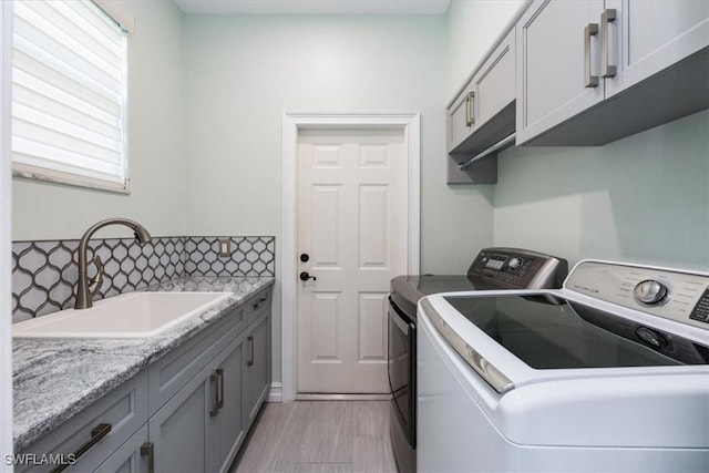 laundry area with cabinets, washer and clothes dryer, and sink