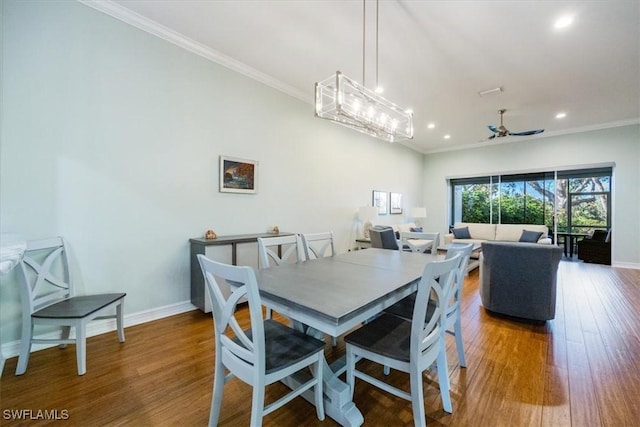 dining space featuring crown molding, wood-type flooring, and ceiling fan with notable chandelier