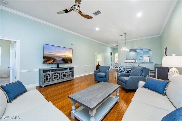 living room featuring wood-type flooring, ornamental molding, and ceiling fan