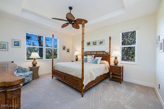 bedroom featuring light carpet, a raised ceiling, and ceiling fan