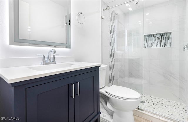 bathroom featuring toilet, a shower with door, and vanity