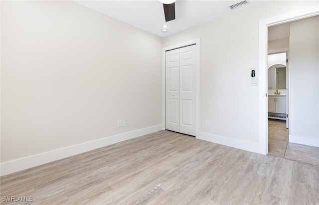 unfurnished bedroom featuring ceiling fan, light hardwood / wood-style flooring, and a closet