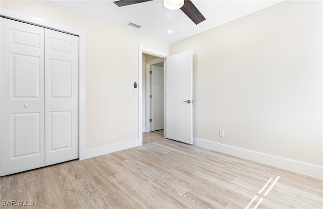 unfurnished bedroom with light hardwood / wood-style flooring, ceiling fan, a closet, and a textured ceiling