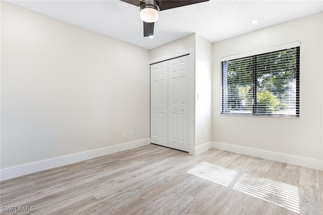 unfurnished bedroom featuring light wood-type flooring, a closet, a textured ceiling, and ceiling fan