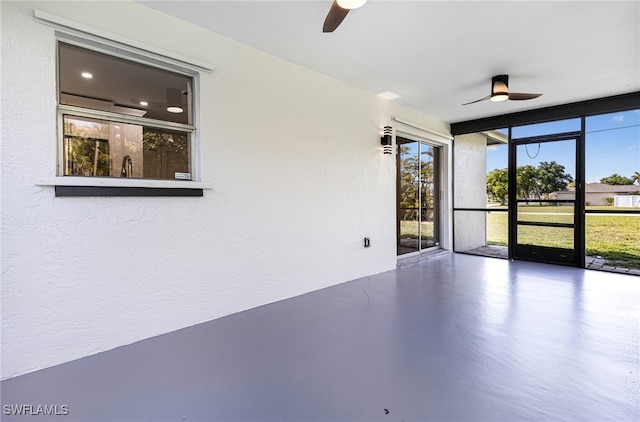 spare room with concrete flooring, ceiling fan, and expansive windows