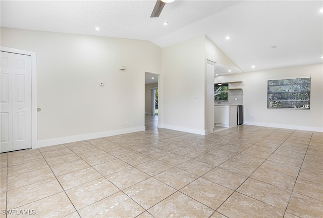 empty room featuring ceiling fan, light tile patterned flooring, vaulted ceiling, and a textured ceiling