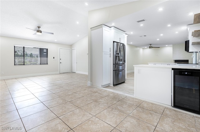 kitchen with white cabinetry, stainless steel fridge, sink, ceiling fan, and beverage cooler