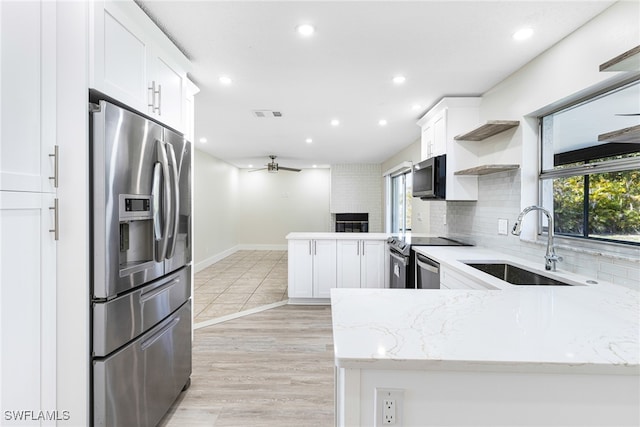 kitchen with kitchen peninsula, sink, ceiling fan, appliances with stainless steel finishes, and white cabinets