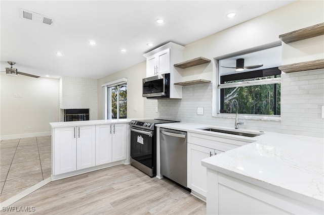 kitchen featuring appliances with stainless steel finishes, sink, light stone counters, ceiling fan, and white cabinets