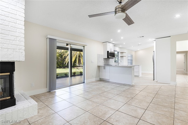 unfurnished living room with light tile patterned floors, ceiling fan, and a textured ceiling