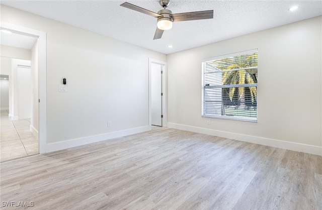 spare room featuring light wood-type flooring, ceiling fan, and a textured ceiling