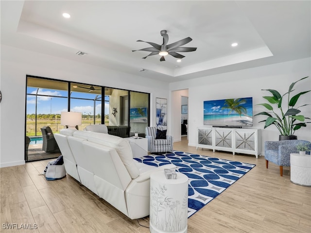 living room with a raised ceiling and light hardwood / wood-style flooring