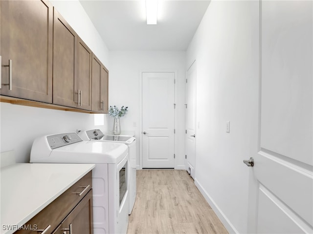 laundry area with cabinets, washer and dryer, and light hardwood / wood-style flooring