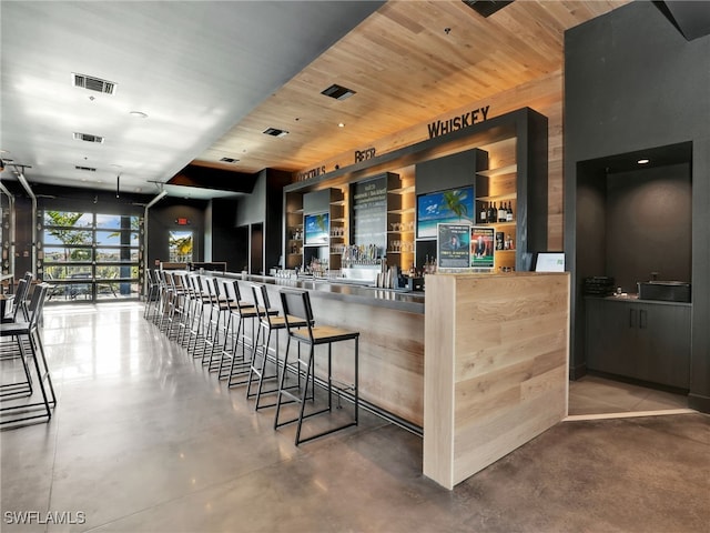 bar featuring concrete flooring and wood ceiling