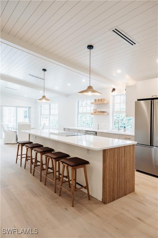 kitchen with a large island, decorative light fixtures, a wealth of natural light, and appliances with stainless steel finishes