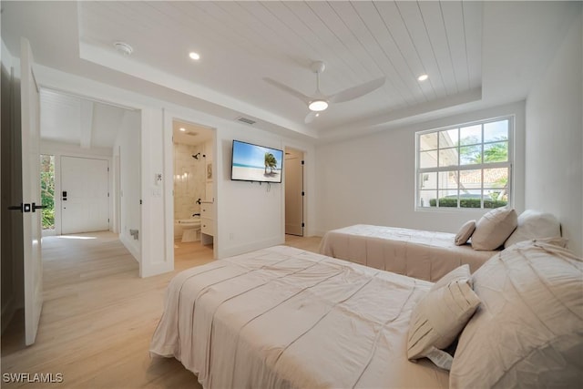 bedroom with light wood finished floors, visible vents, a tray ceiling, and recessed lighting