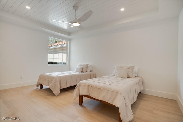 bedroom with a tray ceiling, light wood-type flooring, wood ceiling, and baseboards