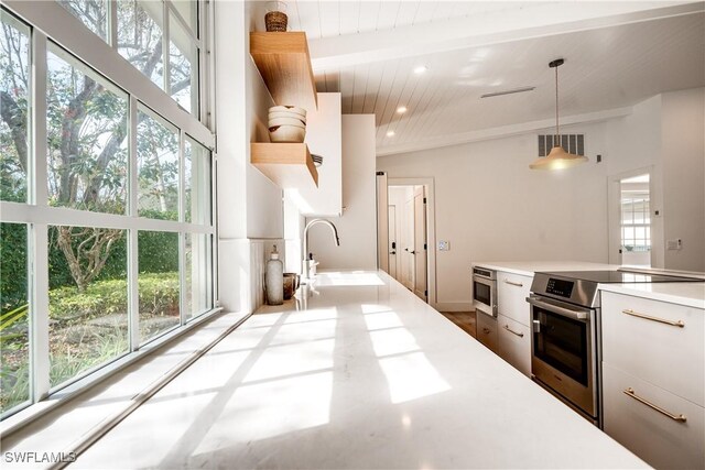 kitchen with visible vents, light countertops, stainless steel range with electric cooktop, open shelves, and beam ceiling