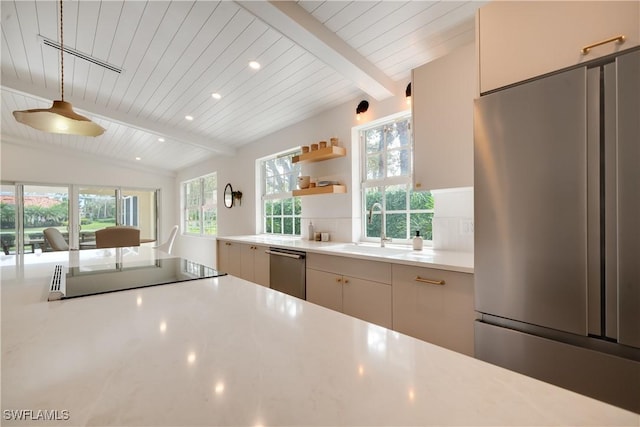 kitchen featuring appliances with stainless steel finishes, a healthy amount of sunlight, light countertops, and vaulted ceiling with beams