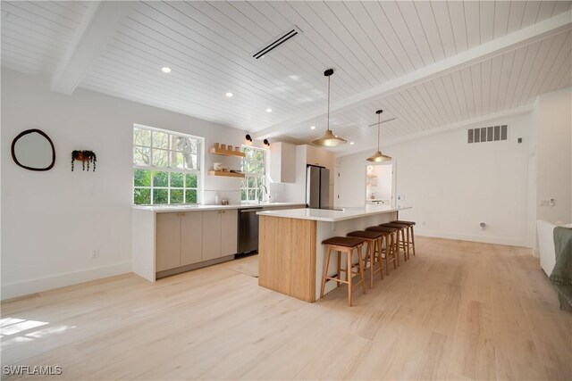 kitchen featuring visible vents, beamed ceiling, a center island, and stainless steel appliances