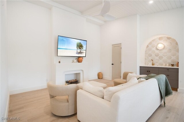 living area featuring a high ceiling, light wood-style flooring, and baseboards