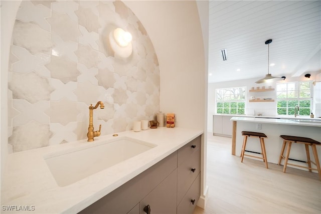 interior space with a kitchen breakfast bar, light countertops, a sink, and pendant lighting