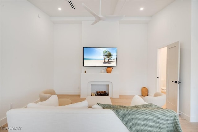 living room featuring light wood finished floors, a fireplace, visible vents, and baseboards