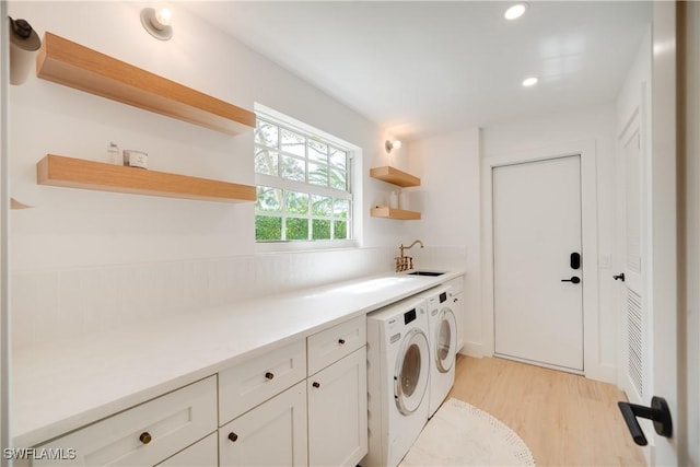 clothes washing area with recessed lighting, cabinet space, light wood-style floors, washing machine and dryer, and a sink