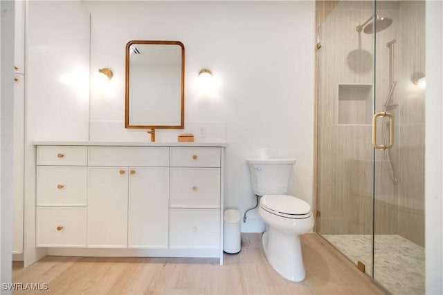 bathroom featuring vanity, toilet, wood finished floors, and a stall shower