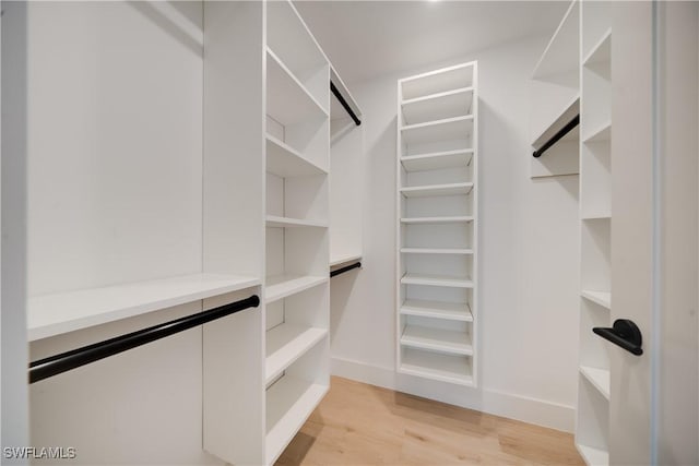 walk in closet with light wood-style floors