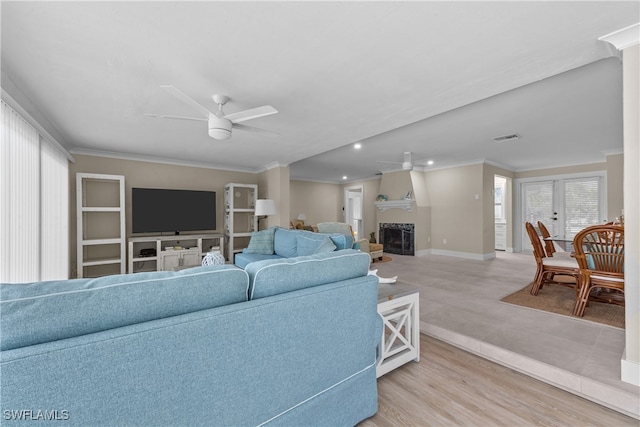 living room with ornamental molding, ceiling fan, and light wood-type flooring