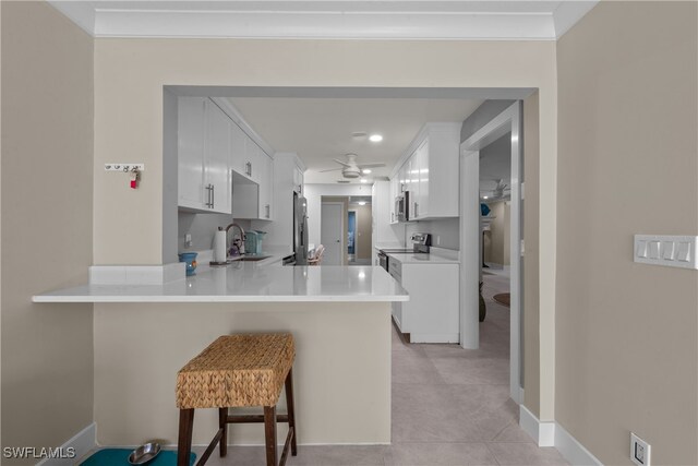 kitchen with a breakfast bar area, stainless steel appliances, kitchen peninsula, and white cabinets