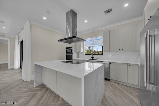 kitchen with crown molding, island range hood, a center island, stainless steel appliances, and light stone countertops