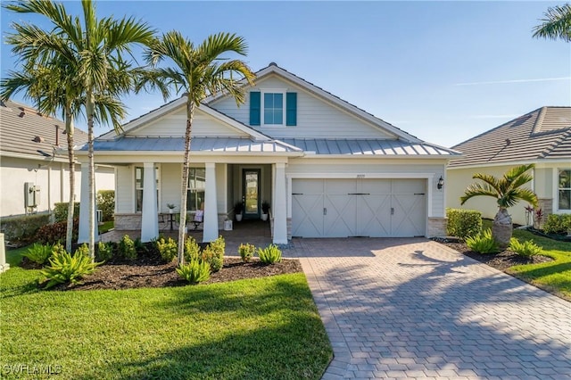 view of front of house with a garage, covered porch, and a front lawn