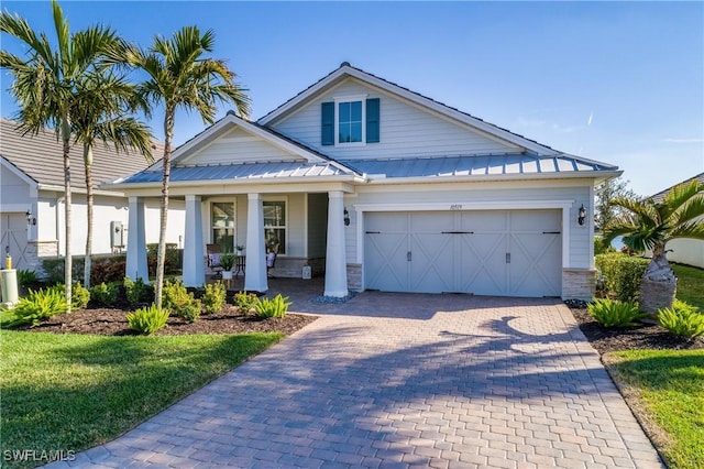 view of front of property featuring a garage, a porch, and a front lawn