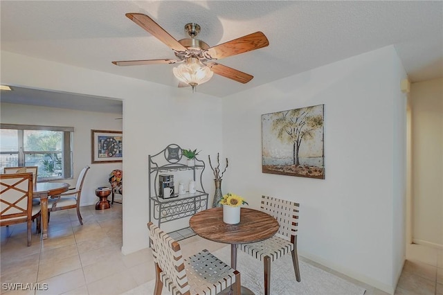 tiled dining area with ceiling fan and a textured ceiling