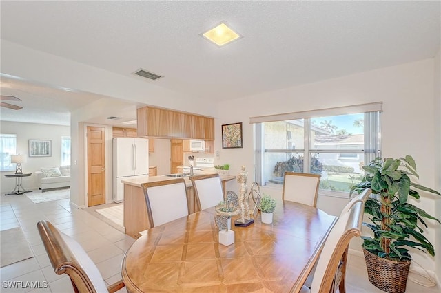 tiled dining space featuring ceiling fan